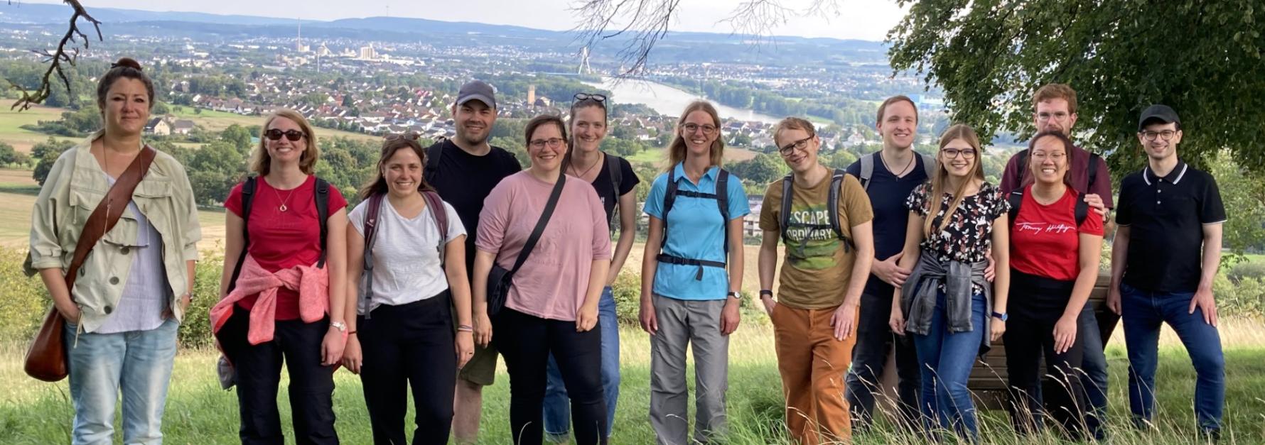 Mehrere Menschen schauen zufrieden in eine Kamera. Sie stehen auf einem Aussichtspunkt mit Blick ins Neuwieder Becken
