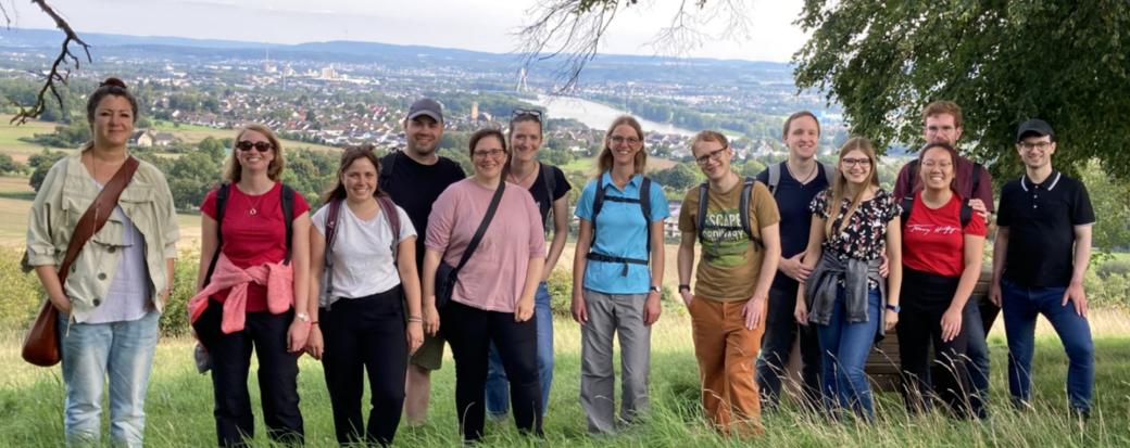 Mehrere Menschen schauen zufrieden in eine Kamera. Sie stehen auf einem Aussichtspunkt mit Blick ins Neuwieder Becken