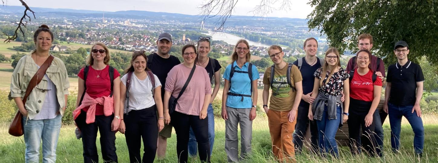 Mehrere Menschen schauen zufrieden in eine Kamera. Sie stehen auf einem Aussichtspunkt mit Blick ins Neuwieder Becken